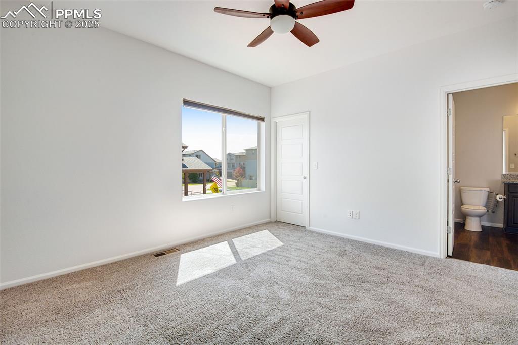 Image 17 of 39: Unfurnished primary bedroom featuring dark colored carpet, a ceiling fan, a