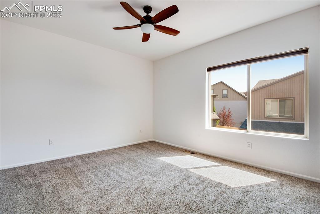 Image 18 of 39: Unfurnished primary room with carpet floors and a ceiling fan