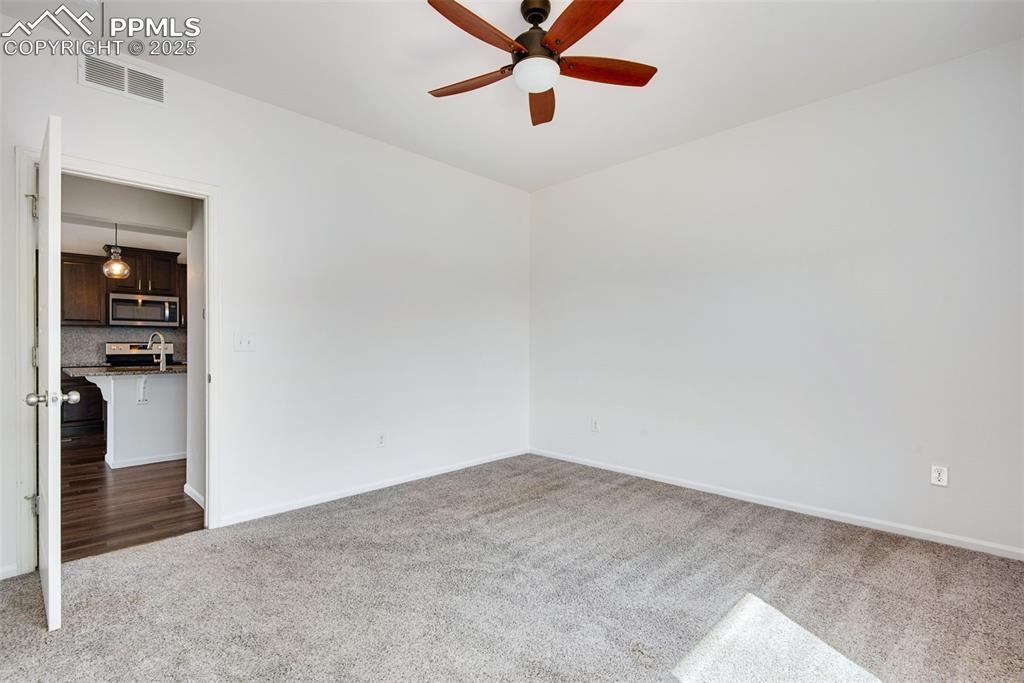 Image 19 of 39: Unfurnished primary room with carpet floors and a ceiling fan