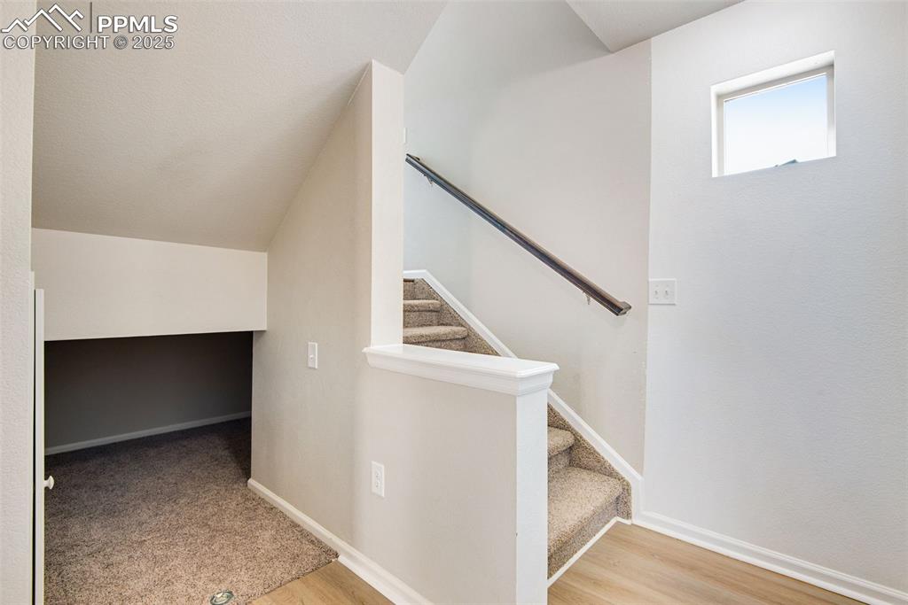 Image 21 of 39: Lower stairway with luxury vinyl finished floors and an understair storage