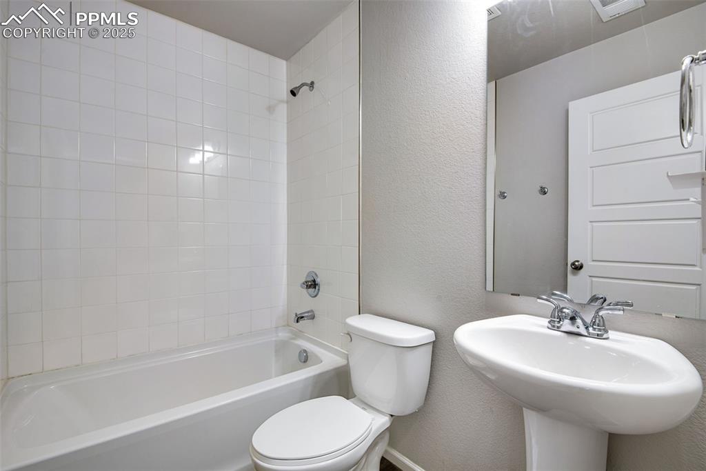Image 25 of 39: Full bath featuring a textured wall and shower combination