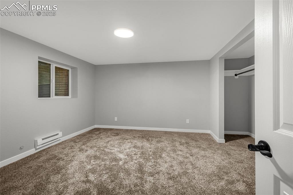Image 23 of 37: Unfurnished bedroom with carpet floors, a baseboard heating unit, and a clo