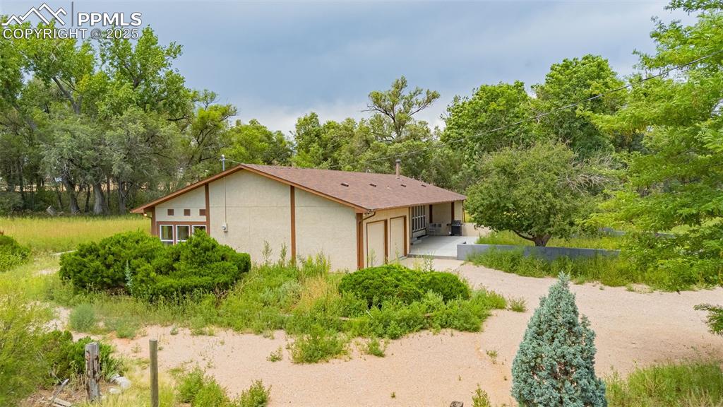 Image 27 of 37: View of side of property with an attached garage, driveway, and stucco sidi