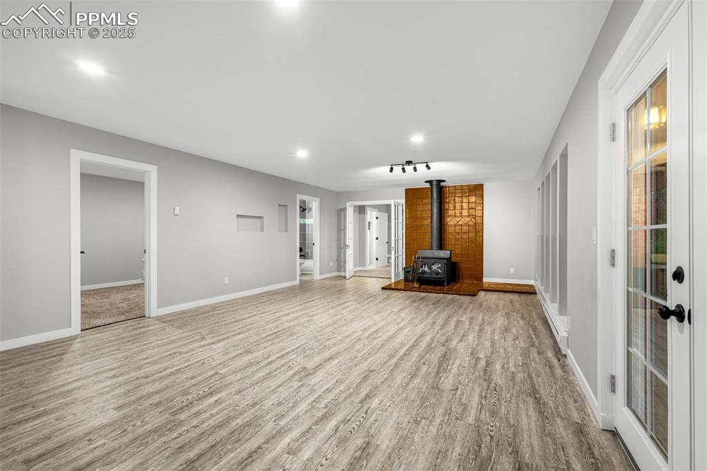Image 4 of 37: Unfurnished living room featuring a wood stove, wood finished floors, and r