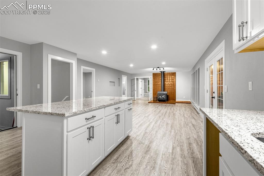 Image 7 of 37: Kitchen with a wood stove, light wood finished floors, recessed lighting, w