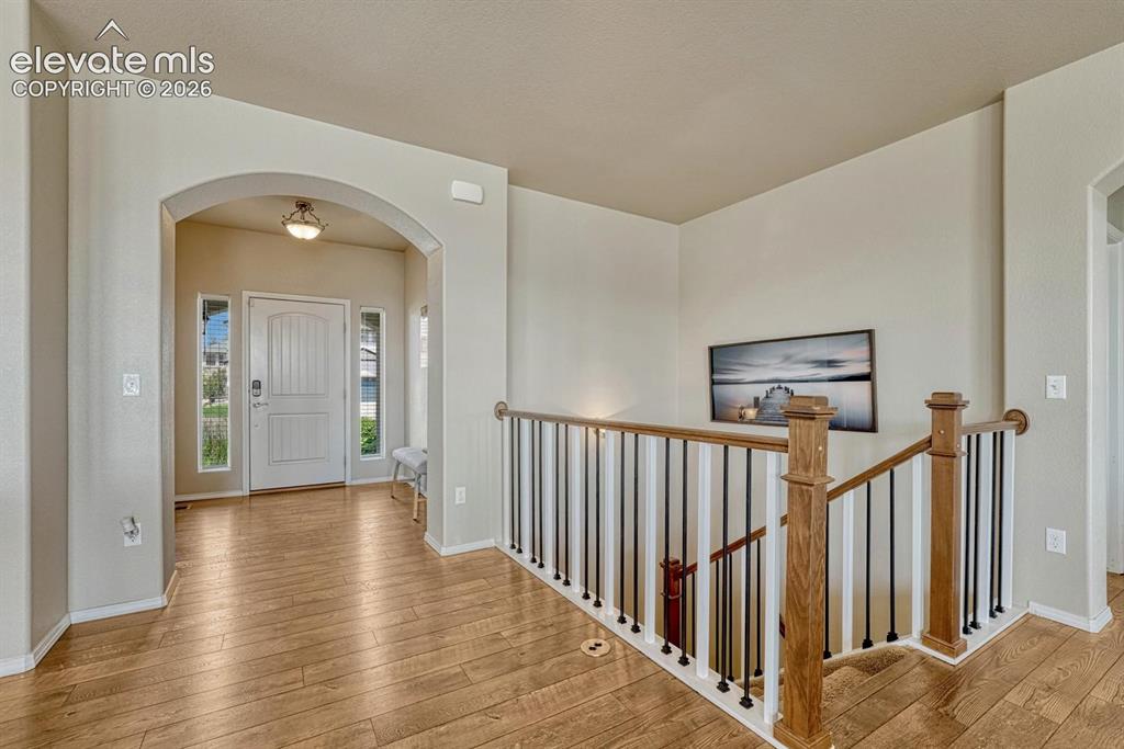 Image 14 of 50: Interior front foyer with gleaming LVP flooring and wood and iron rails to