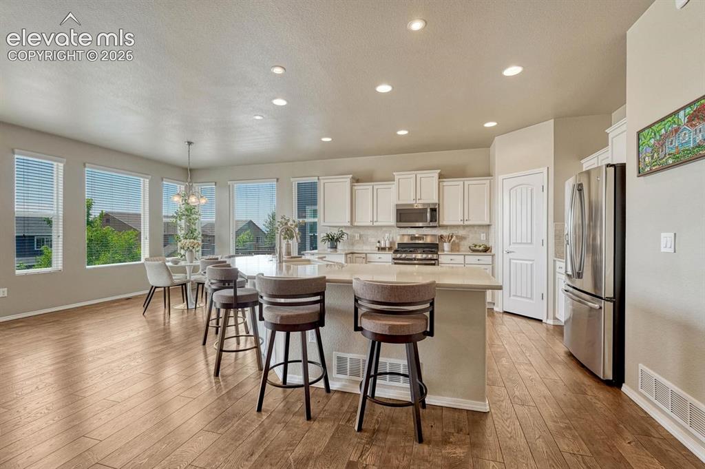 Image 19 of 50: Upgraded island kitchen and dining area with wall of windows and remarkable