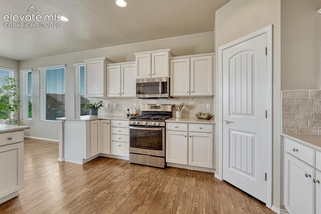 Image 21 of 50: Kitchen pantry and view of the gas range oven and built-in microwave oven.