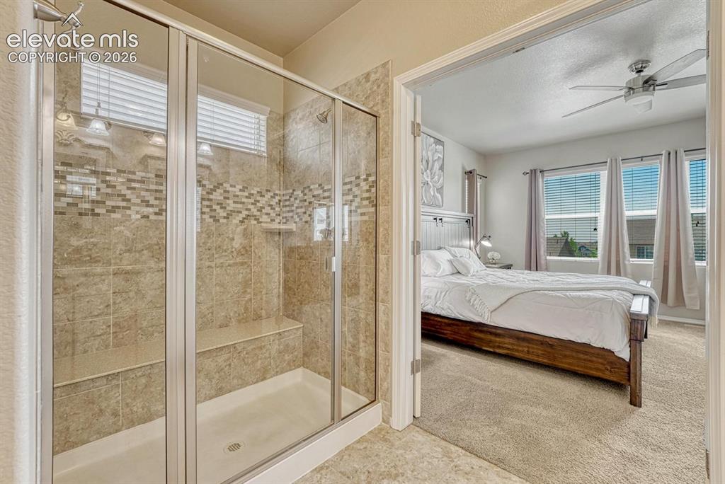 Image 30 of 50: Enclosed tiled shower with built-in seat in the Primary Bathroom.