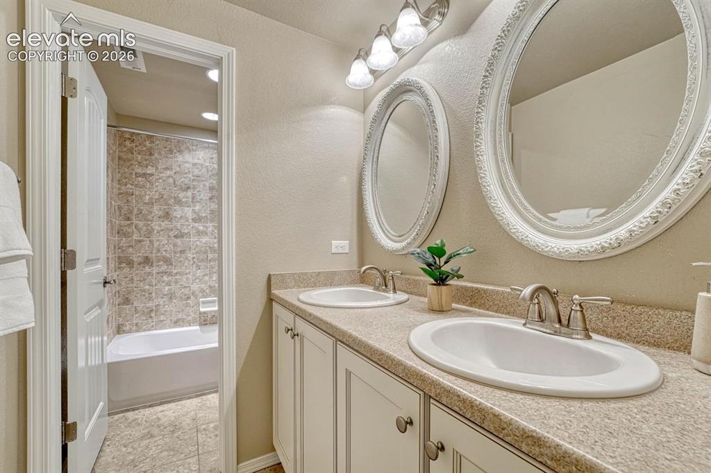 Image 37 of 50: Basement Full Bathroom with dual sink vanity, framed mirrors, and tiled tub