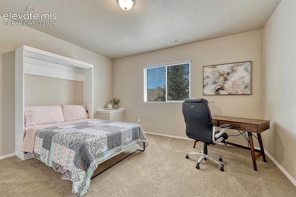 Image 42 of 50: Basement Bedroom #5 has neutral carpet and space for a desk area.