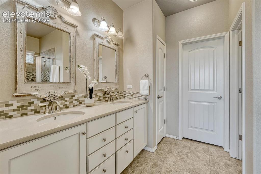 Image 9 of 50: Primary Bathroom with tile flooring, a dual sink quartz vanity, framed mirr