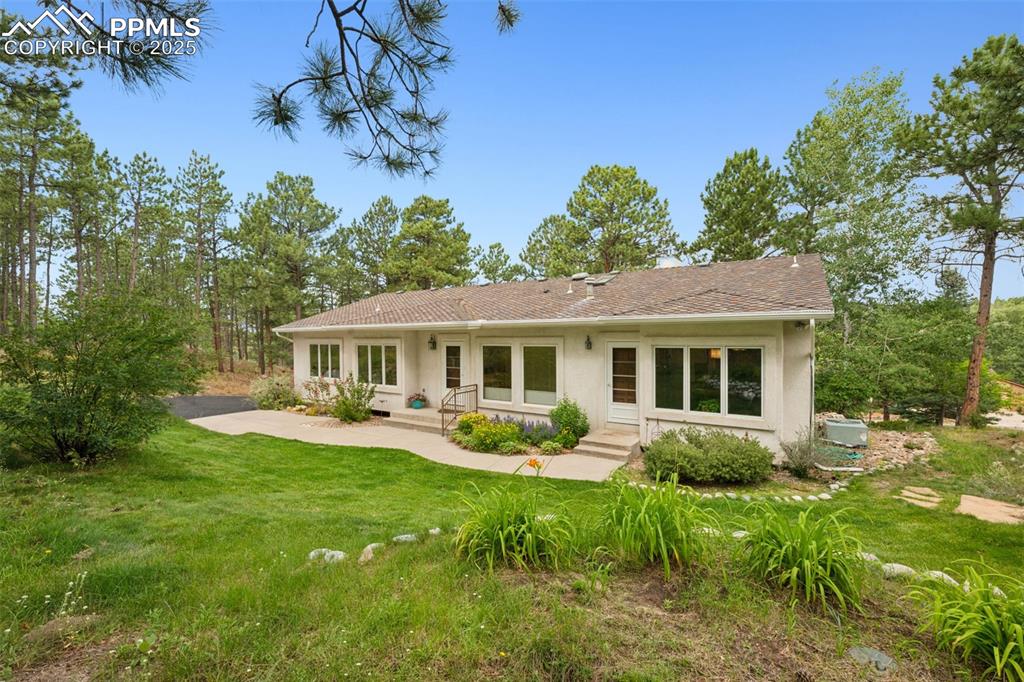 Caption: Rear view of house with a lawn and stucco siding