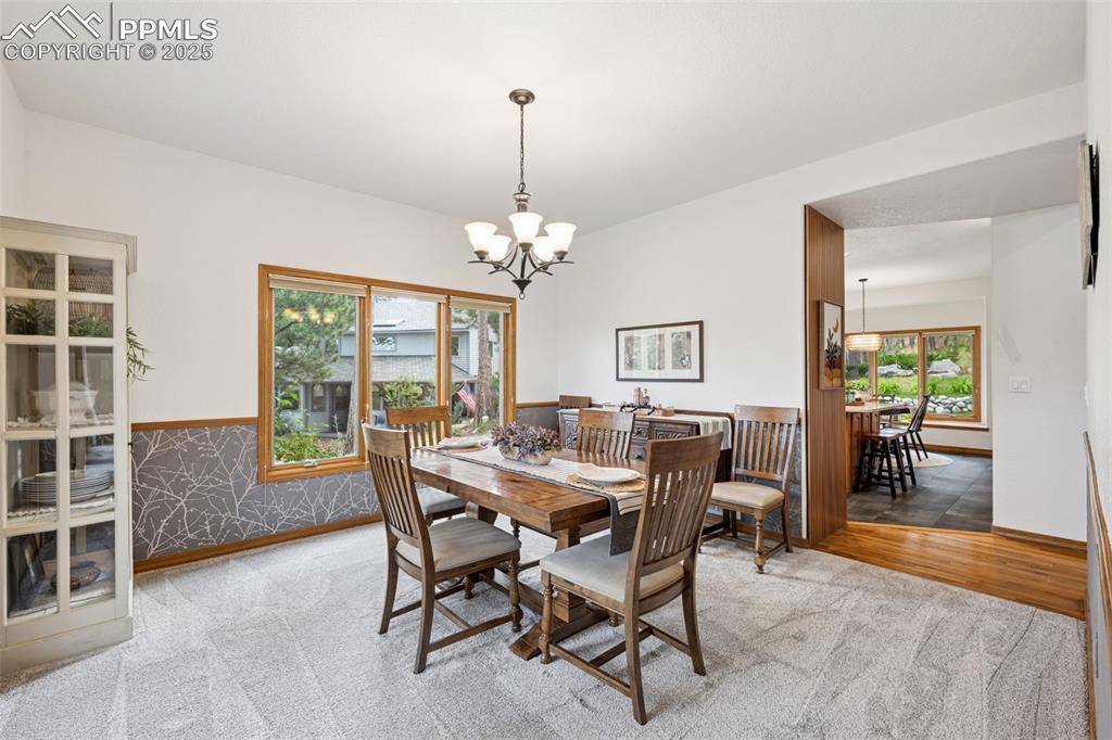 Image 10 of 39: Carpeted dining space with a chandelier and custom wainscoting