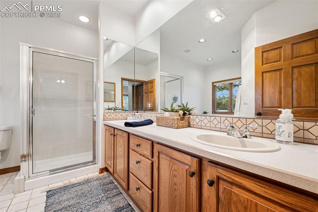 Image 21 of 39: Full bath featuring double vanity, a shower stall, soaker tub, tile pattern