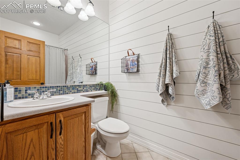 Image 25 of 39: Bathroom featuring tile patterned floors, vanity, backsplash, wooden walls,