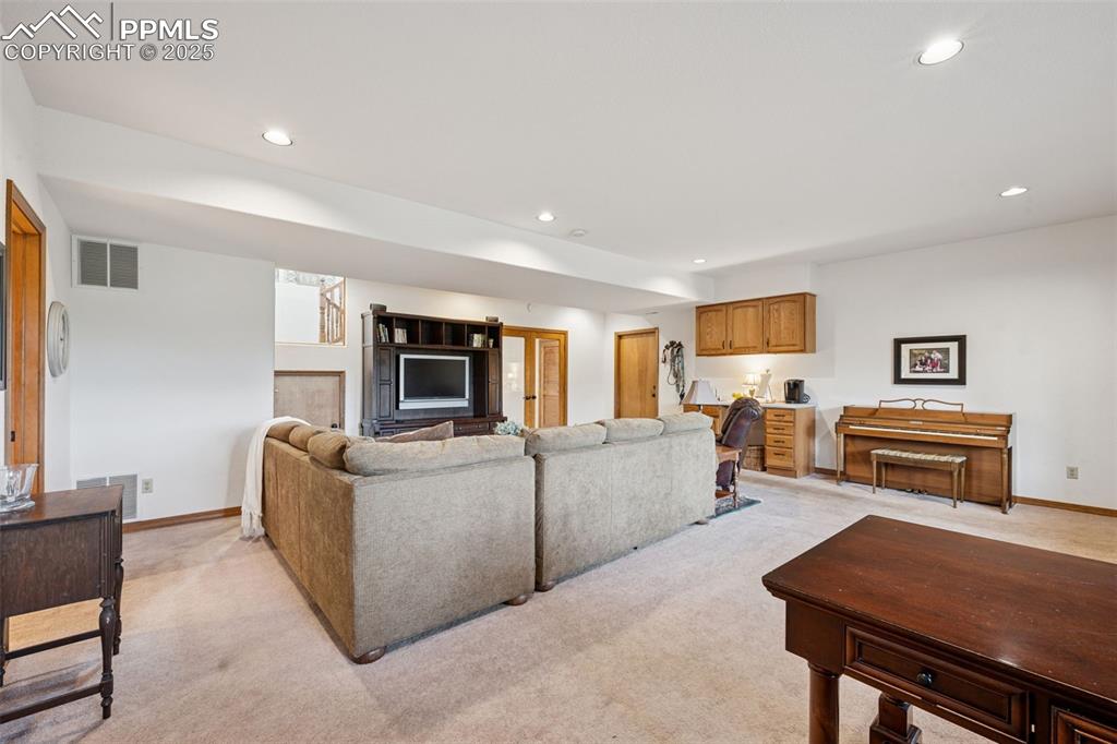 Image 32 of 39: Living area with recessed lighting and light carpet