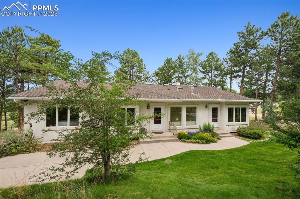Image 38 of 39: Back of property featuring stucco siding and a lawn