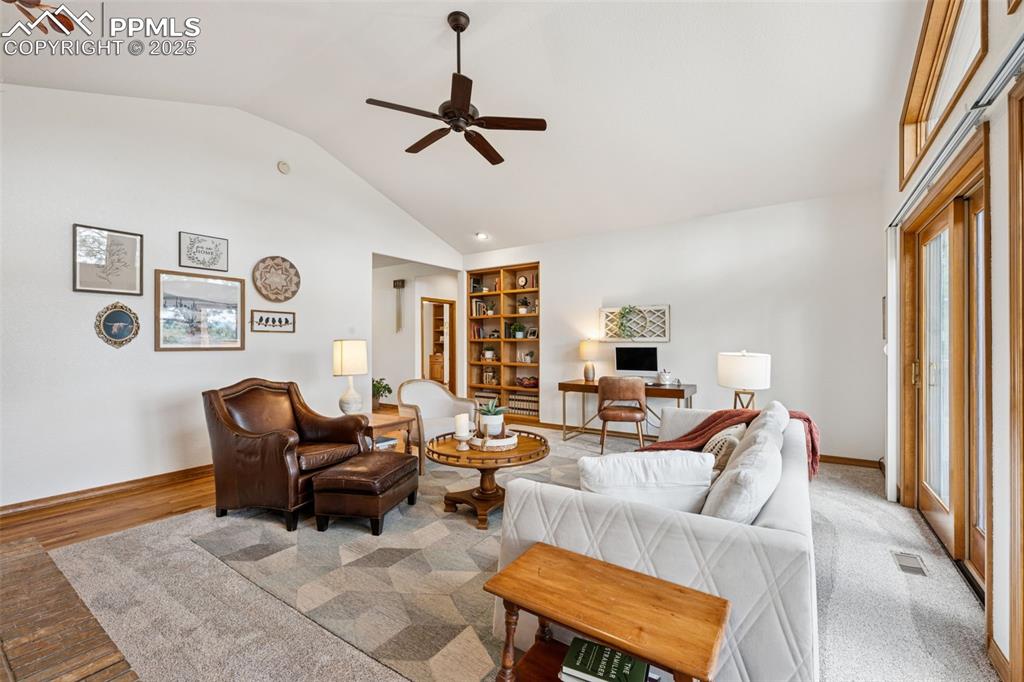 Image 8 of 39: Living area with ceiling fan, built in features, high vaulted ceiling, and