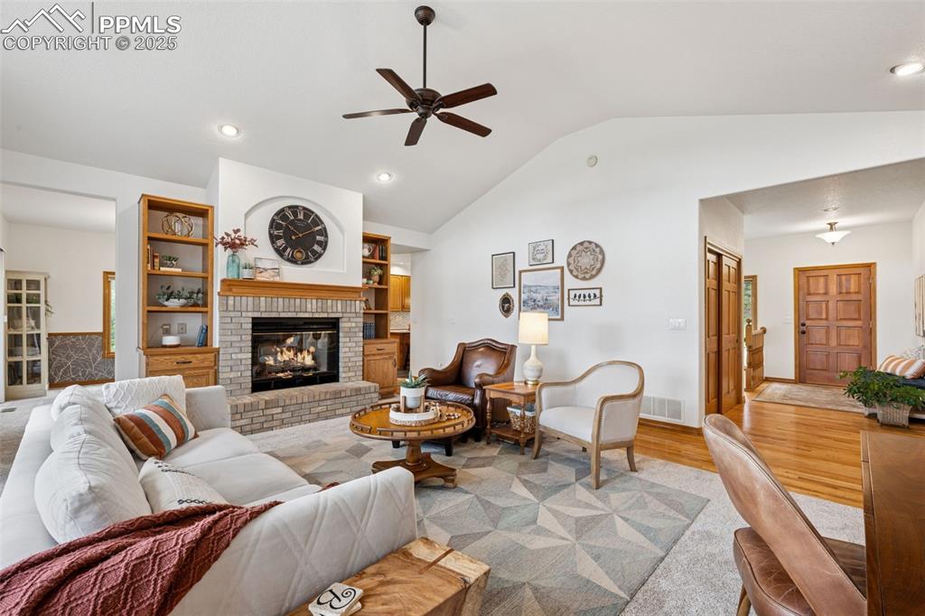 Image 9 of 39: Living area with light wood-style flooring, vaulted ceiling, recessed light
