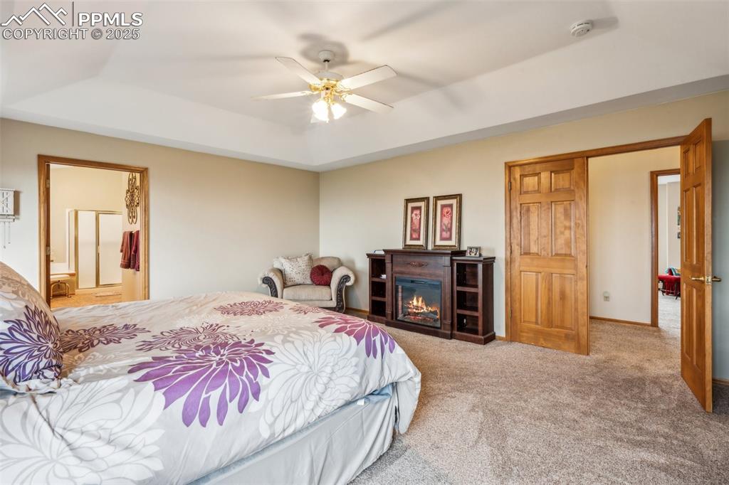 Image 22 of 43: Bedroom featuring a raised ceiling, carpet, a ceiling fan, and connected ba