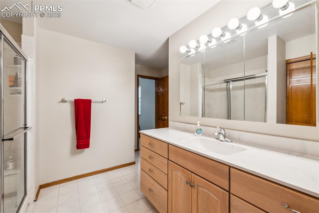 Image 34 of 43: Full bath with vanity, a stall shower, and baseboards