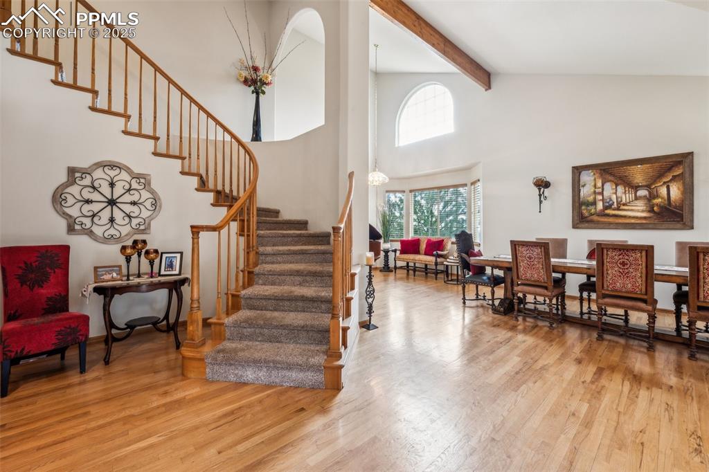 Image 4 of 43: Stairs with wood finished floors, beam ceiling, and high vaulted ceiling