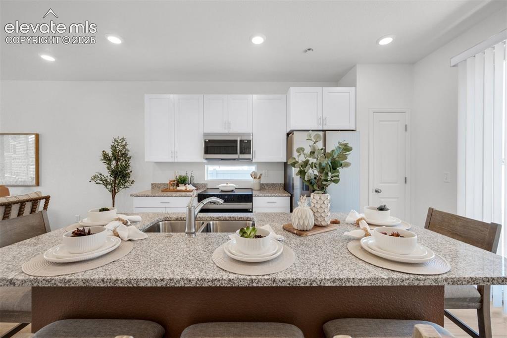 Image 10 of 35: Kitchen featuring white cabinetry, stainless steel appliances, speckled cou