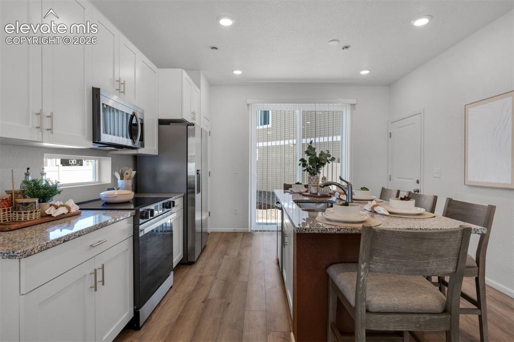 Image 11 of 35: Kitchen featuring white cabinetry, stainless steel appliances, granite coun