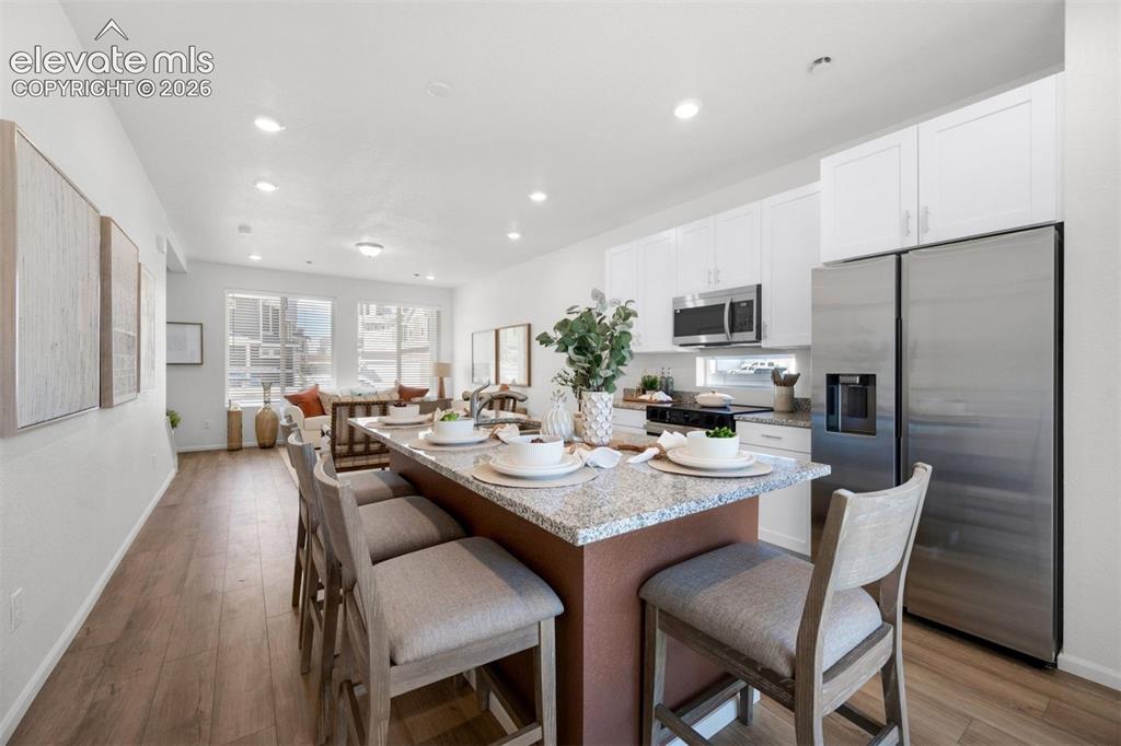 Image 12 of 35: Open-concept living space featuring wood-finish flooring, recessed lighting