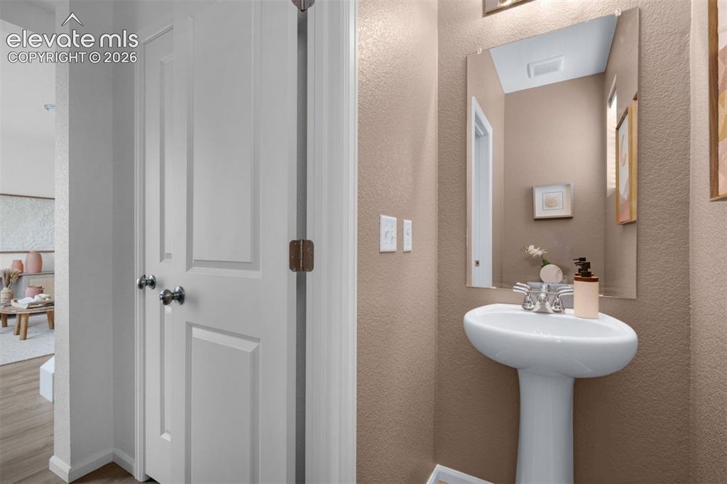 Image 15 of 35: Pedestal sink with chrome faucet, wall-mounted mirror, and neutral wall fin