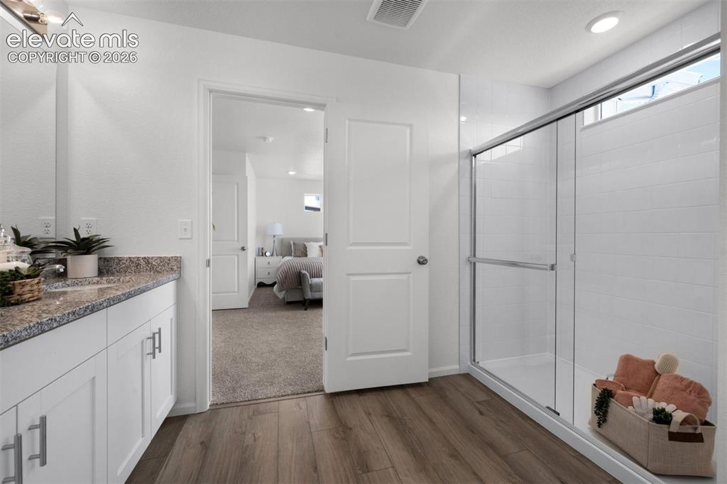Image 16 of 35: Wood-finish flooring with a white vanity featuring a speckled countertop
*
