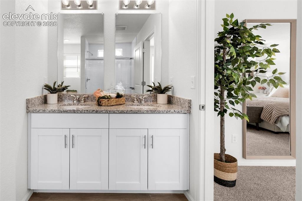 Image 17 of 35: Dual vanity with granite countertop, individual sinks, and white shaker-sty