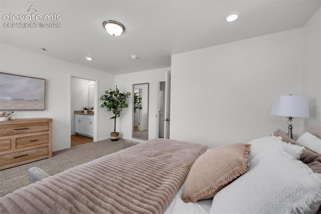 Image 18 of 35: Spacious primary bedroom featuring neutral décor, carpeted flooring, recess