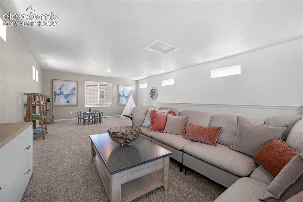 Image 32 of 35: Spacious carpeted room featuring multiple windows, a ceiling light fixture,