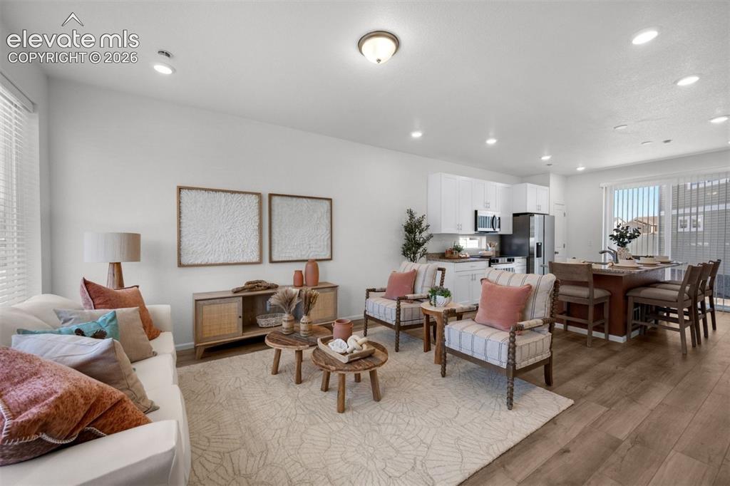 Image 6 of 35: Open-concept living space featuring wood-finish flooring, recessed lighting
