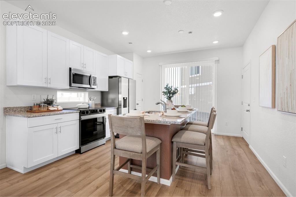 Image 9 of 35: Kitchen featuring wood-finish flooring, white cabinetry, stainless steel ap