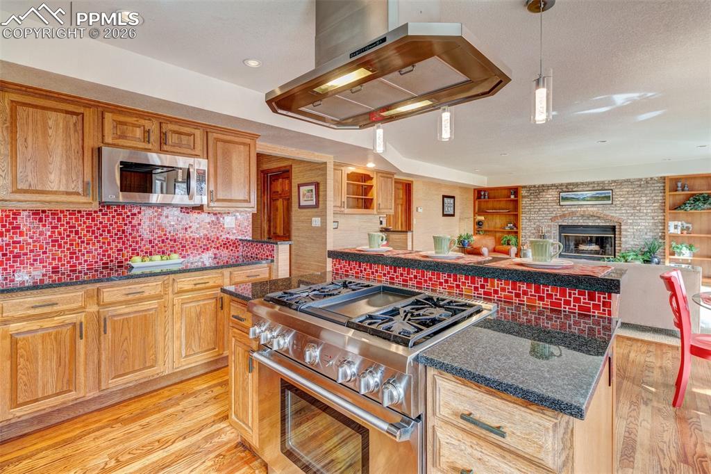 Image 10 of 39: Updated kitchen with stainless appliances, slab granite, and tiled backspla