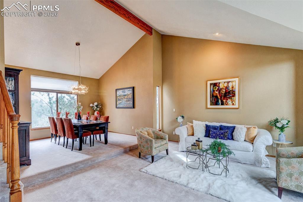 Image 5 of 39: Living room and Dining room with peaked ceiling and great windows