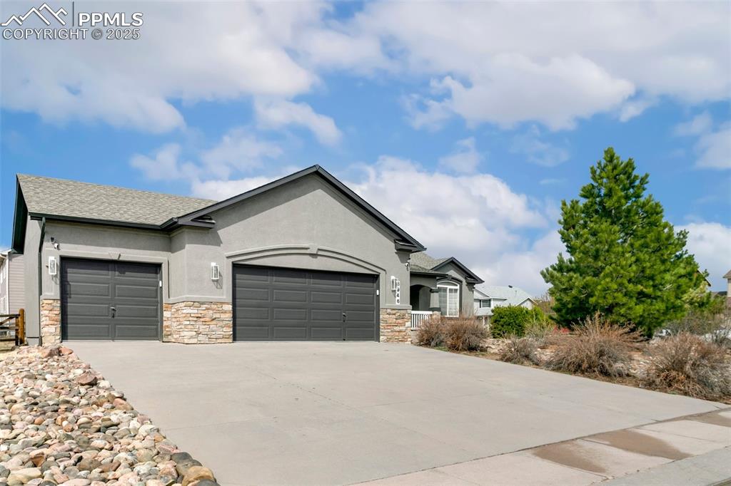 Image 2 of 35: View of front of home with stone siding, an attached garage, stucco siding,