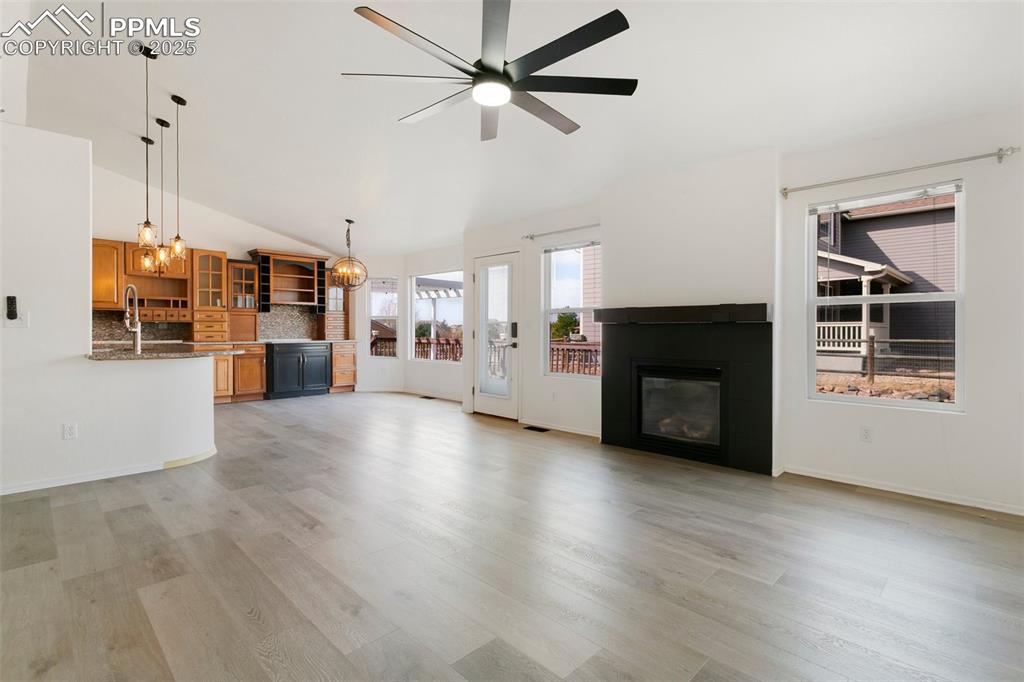 Image 4 of 35: Unfurnished living room with ceiling fan with notable chandelier, high vaul