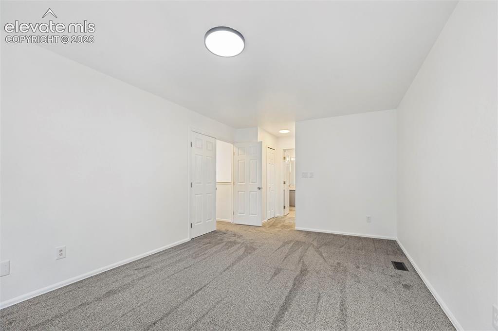 Image 18 of 25: Neutral wall color with gray carpeting and a flush-mount ceiling light