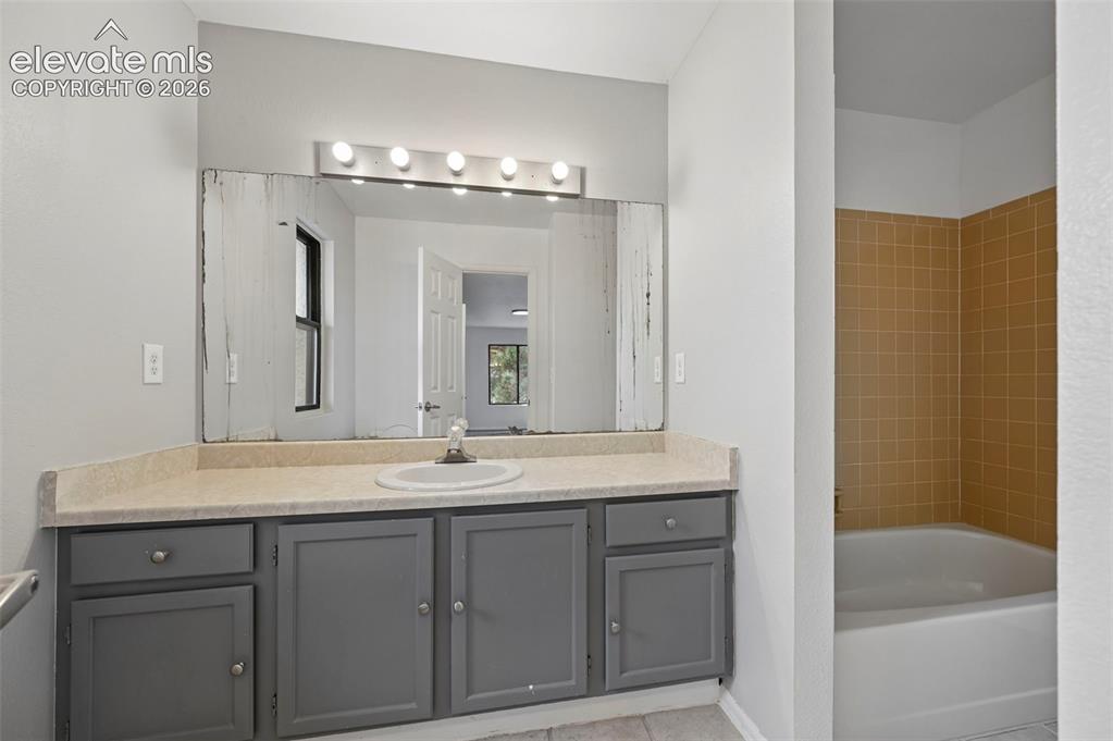 Image 20 of 25: Vanity with integrated sink, light-colored countertop, and gray cabinetry w