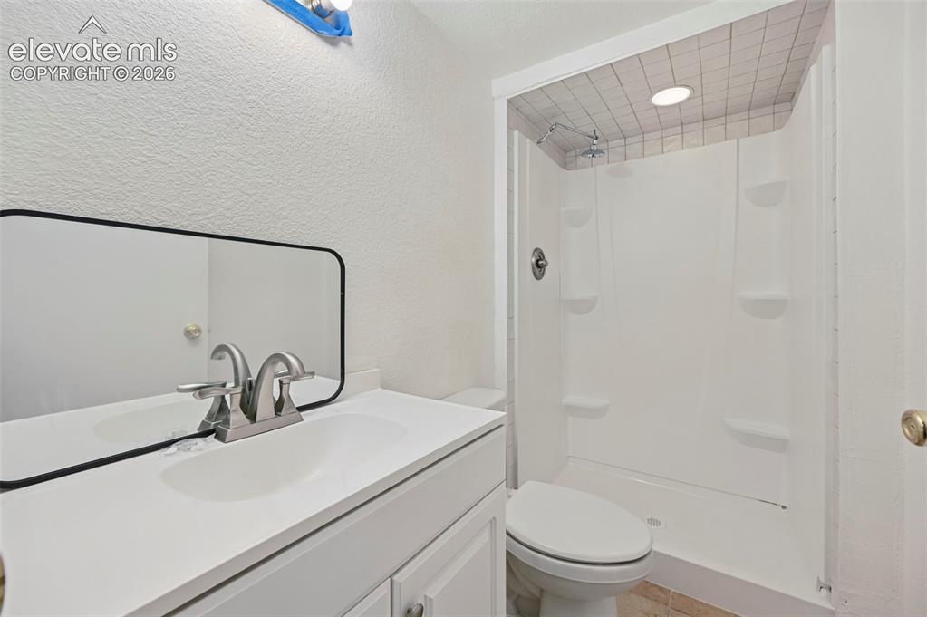 Image 21 of 25: White vanity with integrated sink, brushed nickel faucet, and frameless mir