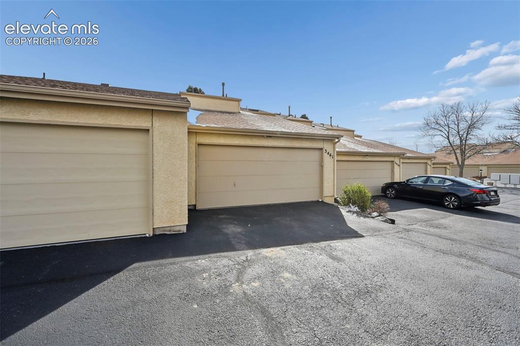 Image 24 of 25: Stucco exterior with multiple attached garages, featuring asphalt driveways