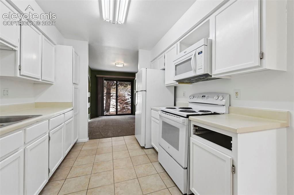 Image 7 of 25: White cabinetry with light-toned countertops, tile flooring, and integrated