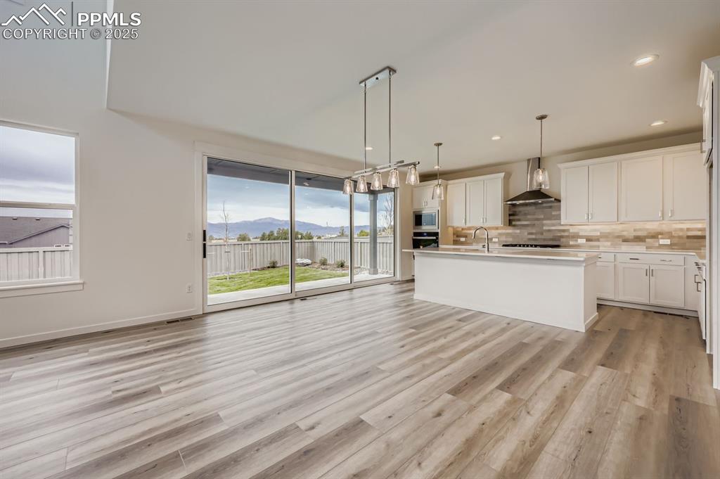 Image 10 of 28: Kitchen with backsplash, a mountain view, pendant lighting, white cabinetry