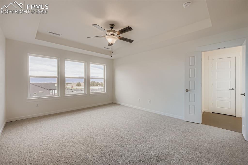 Image 14 of 28: Empty room featuring a tray ceiling and light carpet
