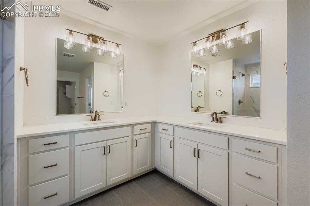 Image 16 of 28: Bathroom with two vanities and a marble finish shower