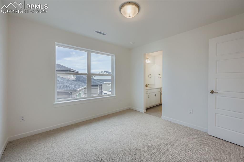 Image 18 of 28: Unfurnished bedroom with light carpet and connected bathroom